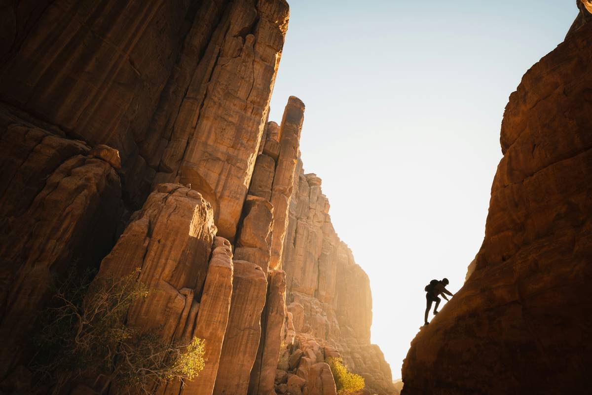 Climber testing anchors for rock climbing on multi-pitch route